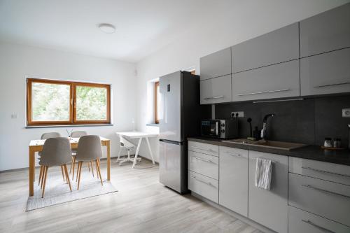 uma cozinha com armários brancos e uma mesa e cadeiras em The Dante Villa Apartments em Praga