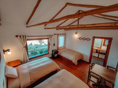1 dormitorio con 2 camas y ventana en Ecolodge K'arasirca en Comunidad Yumani