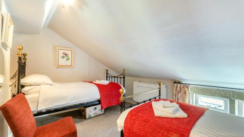 a attic bedroom with two beds and a chair at Rose Cottage in Youlgreave