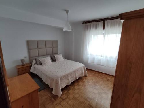 - une chambre blanche avec un lit et une fenêtre dans l'établissement Acogedor piso en primera línea de mar- 8 huéspedes, à A Guarda