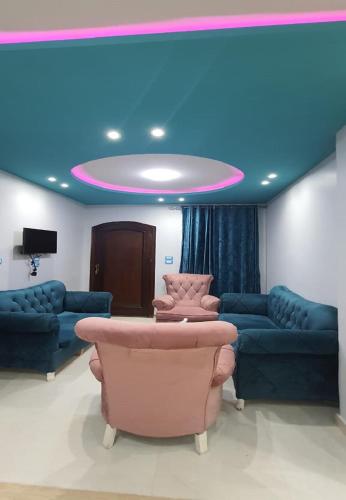 une chambre avec des canapés et un plafond bleu dans l'établissement M&H Apartment, à Dumyāţ al Jadīdah