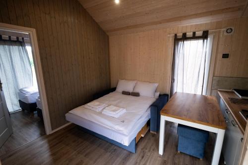 a small room with a bed and a wooden table at Kwiatkowo - całoroczny kompleks z baliami i letnią plażą in Wünschelburg