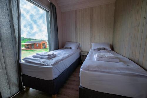 two beds in a small room with a window at Kwiatkowo - całoroczny kompleks z baliami i letnią plażą in Wünschelburg