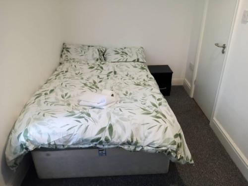 a bed in a room with a white bedspread with leaves at Ensuite double-bed (R4) close to Burnley city centre in Burnley