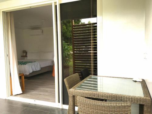 eine Terrasse mit einem Glastisch und ein Zimmer mit einem Bett in der Unterkunft TAHITI - Studio Ata in Pirae