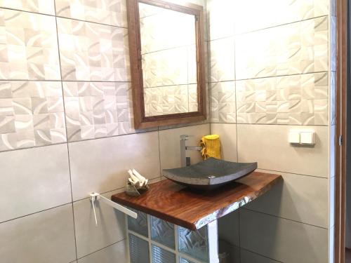 ein Badezimmer mit einem Waschbecken auf einer Holztheke in der Unterkunft TAHITI - Studio Ata in Pirae