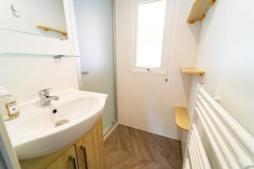 ein Bad mit einem Waschbecken und einem Fenster in der Unterkunft Mobil-home 6/8 personnes - Camping Siblu **** Domaine de Dugny in Onzain