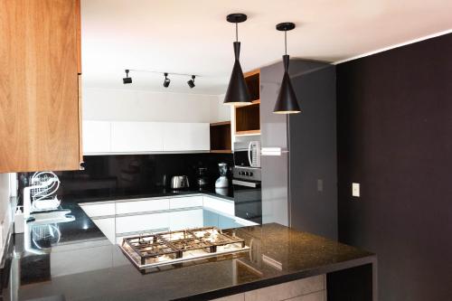 cocina con armarios blancos y encimera negra en Casa Padvon- Private Residence with espectacular Roof Garden - 3BR 3BTH, en Ciudad de México