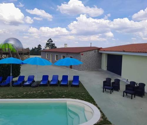 a swimming pool with blue chairs and umbrellas at Bolhas da Montanha in Ribas