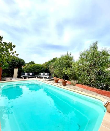 une grande piscine bleue avec des tables et des chaises dans l'établissement Studio Love Les Orangers - Piscine - 15mn plage - 5 kms, à Six-Fours-les-Plages