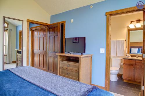a bedroom with a bed with a television and a bathroom at Fire Mountain Two Bedroom Condo in Canmore