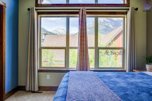 a bedroom with a large window and a blue bed at Fire Mountain Two Bedroom Condo in Canmore