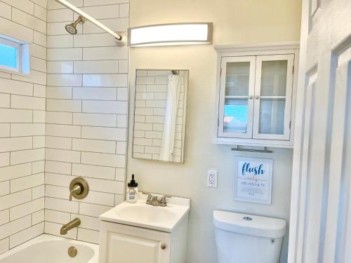 een badkamer met een wastafel, een toilet en een spiegel bij Cozy Beach Cottage with Bicycles in San Diego