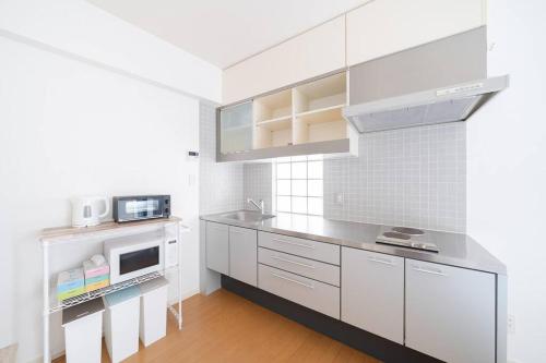 La cuisine est équipée de placards blancs et d'un four micro-ondes. dans l'établissement Granduo 松濤, à Tokyo
