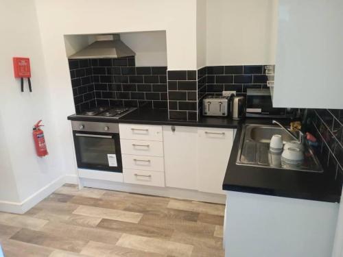 a kitchen with a sink and a stove at Ensuite double-bed (G1) close to Burnley city centre in Burnley