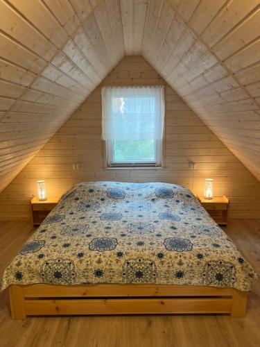 a bed in a small room with a window at Domki nad jeziorem Łąkowa in Gietrzwałd