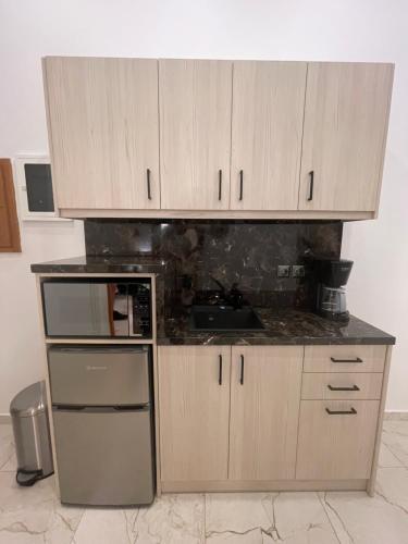 a kitchen with wooden cabinets and a counter top at Emerald Luxury Apartments - ATH Airport in Spáta