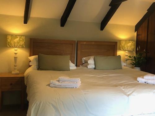 a bedroom with a large white bed with towels on it at Blisland Cottage in Blisland