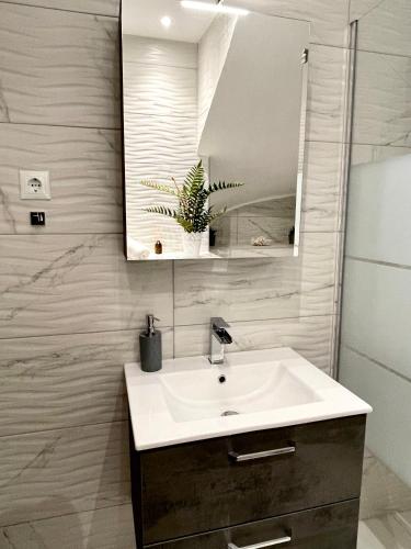 a bathroom with a sink and a mirror at Emerald Luxury Apartments - ATH Airport in Spáta
