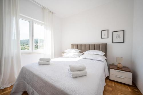 1 dormitorio blanco con 1 cama blanca grande con almohadas blancas en Apartment Mango, en Vinišće