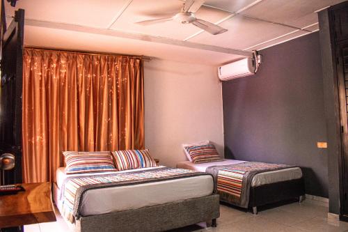 a room with two beds and a ceiling fan at Yosu Hostal in Ríohacha