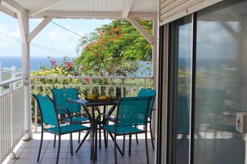 eine Terrasse mit einem Tisch und Stühlen auf dem Balkon in der Unterkunft Villa le flamboyant in Le Marin