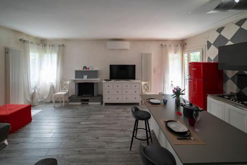 Montecolo Bay 1 في Pilzone: غرفة معيشة مع مطبخ مع دواليب حمراء وطاولة