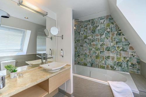 a bathroom with a sink and a tub and a shower at Best Western Plus Hôtel Vannes Centre Ville in Vannes