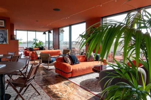 a lobby with orange couches and tables and plants at Radisson Collection Hotel, Santa Sofia Milan in Milan