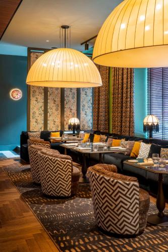 a restaurant with tables and chairs and large lamps at Radisson Collection Hotel, Santa Sofia Milan in Milan