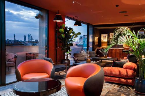 a lobby with orange chairs and tables and a large window at Radisson Collection Hotel, Santa Sofia Milan in Milan