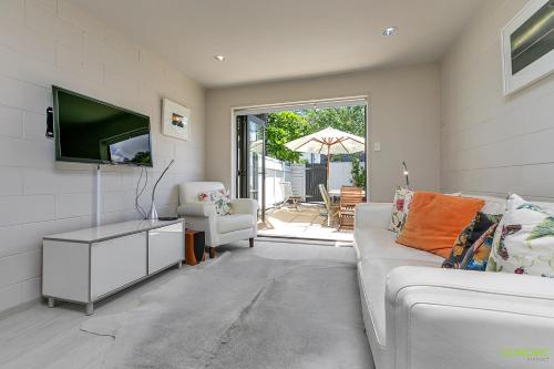 sala de estar con sofá y TV de pantalla plana en QV Sunny Townhouse at Collingwood Street - 1067, en Auckland