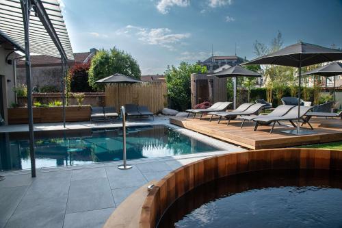 a pool with chairs and an umbrella in a backyard at Best Western Premier Le Chapitre Hotel and Spa in Remiremont