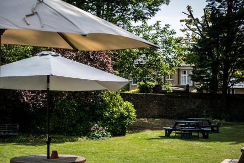 a white umbrella sitting in the grass next to a picnic table at Findon Manor Hotel in Worthing