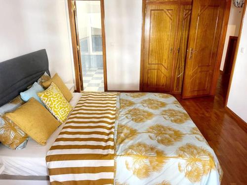 a bedroom with a large bed with yellow and brown pillows at Central Apartment in Belas, Lisbon in Belas