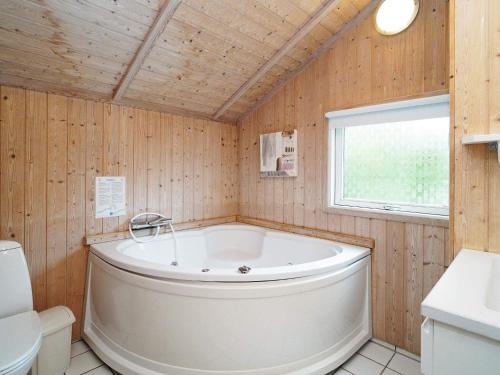 a bath tub in a bathroom with wooden walls at Four-Bedroom Holiday home in Slagelse 2 in Store Kongsmark