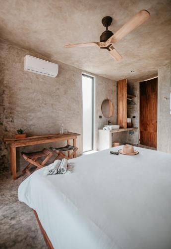 a large white bed in a room with a ceiling fan at Dos Mares Barefoot Luxury in El Cuyo