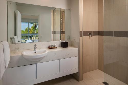 a bathroom with a sink and a shower with a mirror at The Terraces Apartments Denarau in Denarau
