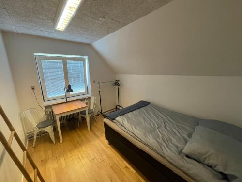 a bedroom with a bed and a desk and a window at Room 19 - Hawkraft kulturhotel in Vestervig