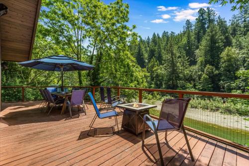 a deck with chairs and a table and an umbrella at Lazy River Lodge - Hot Tub On the River Kayaks in Guerneville
