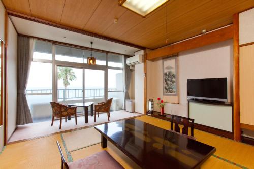 a living room with a dining table and a television at Boyokaku in Amakusa