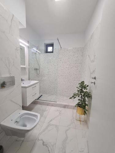 Baño blanco con aseo y lavamanos en apartament 2 camere superb, en Bucarest