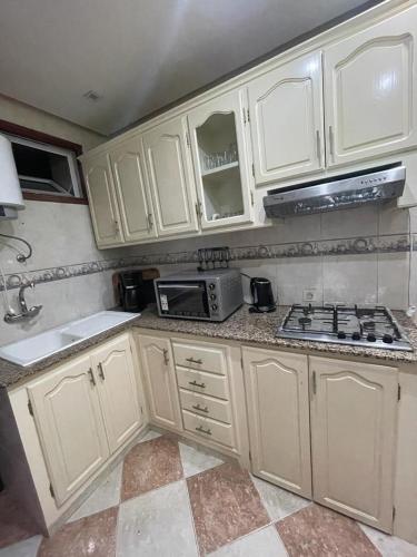 a kitchen with white cabinets and a sink and a microwave at Martil Beach Down Town in Martil