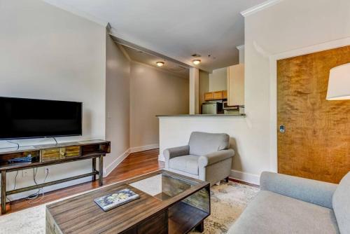 a living room with a tv and a couch and a chair at Loft steps from City Hall and River Street in Savannah