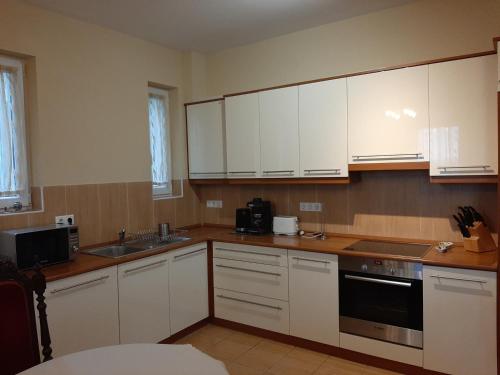 a kitchen with white cabinets and a sink at Villa Hegyalja in Balatonkenese
