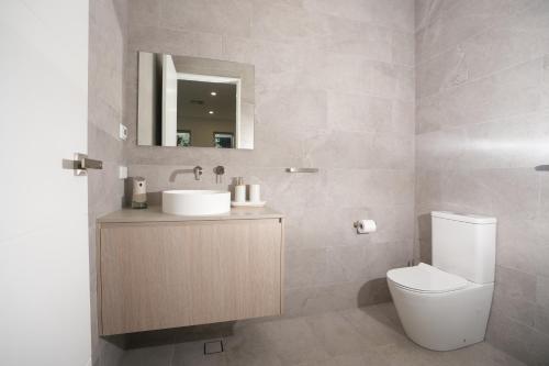 a bathroom with a toilet and a sink and a mirror at Powder Peaks in Jindabyne