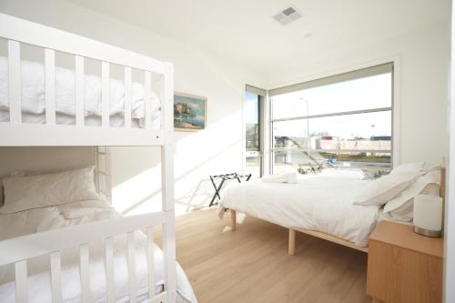 a white bedroom with a bunk bed and a window at Powder Peaks in Jindabyne