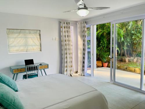 Stay in Style في ديربان: غرفة نوم مع سرير ومكتب وأبواب زجاجية منزلقة