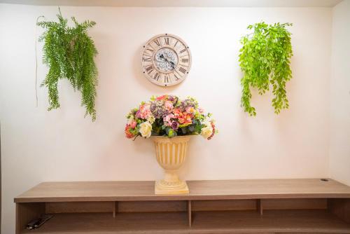 a vase on a table with a clock and flowers at BLISS BOUTIQUE HOTEL BOGOTA in Bogotá