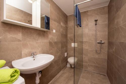 La salle de bains est pourvue d'un lavabo et d'une douche en verre. dans l'établissement Apartments with a parking space Split - 21525, à Split